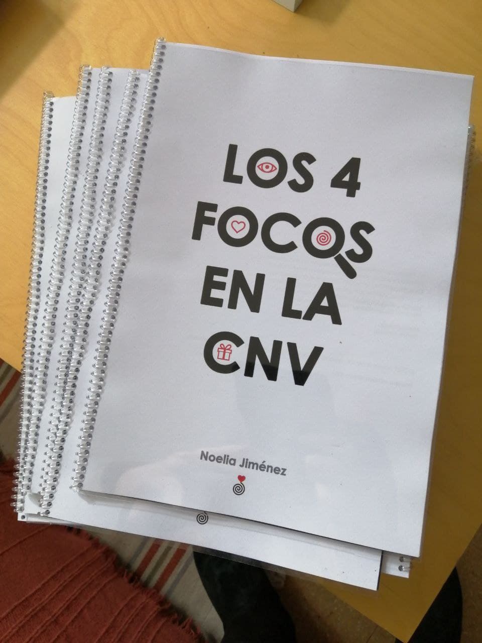 Una pila de folletos encuadernados en espiral titulados "Los 4 Focos en la CNV", de Noelia Jiménez, colocados sobre una mesa de color claro.