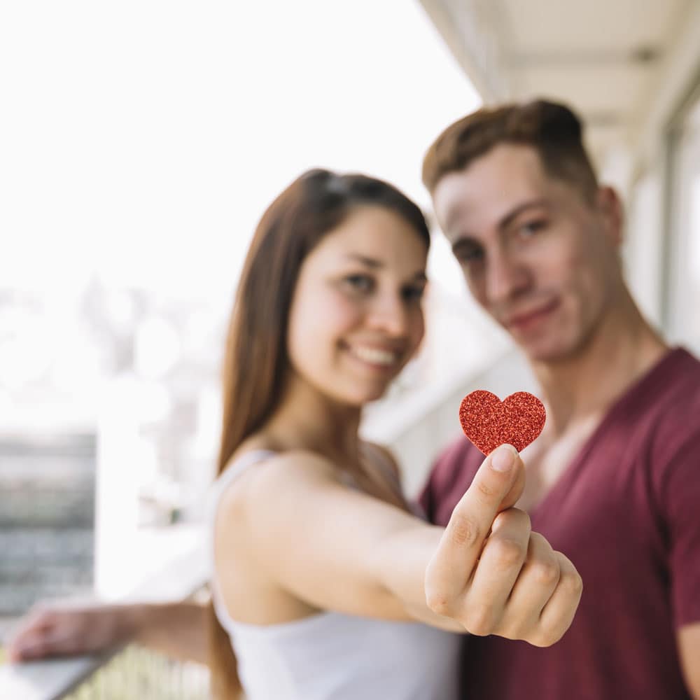 Joven pareja mostrando un corazón de fieltro en un taller de comunicación.