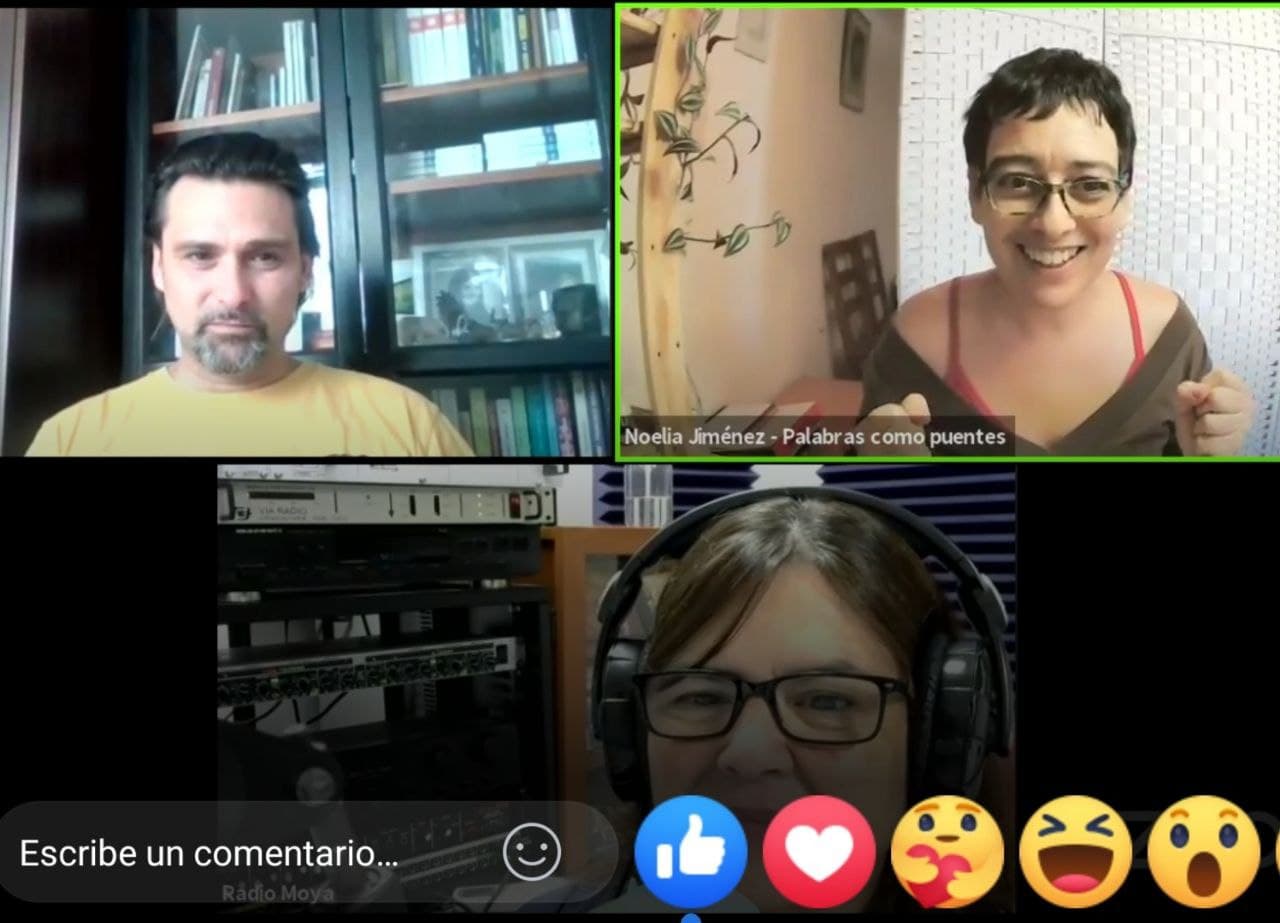 Tres personas participan en una videollamada; dos sonríen. En la parte inferior de la pantalla aparecen iconos de reacción a las redes sociales y un cuadro de comentarios.