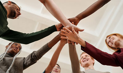 Grupo de personas uniendo las manos en señal de unión y trabajo en equipo.