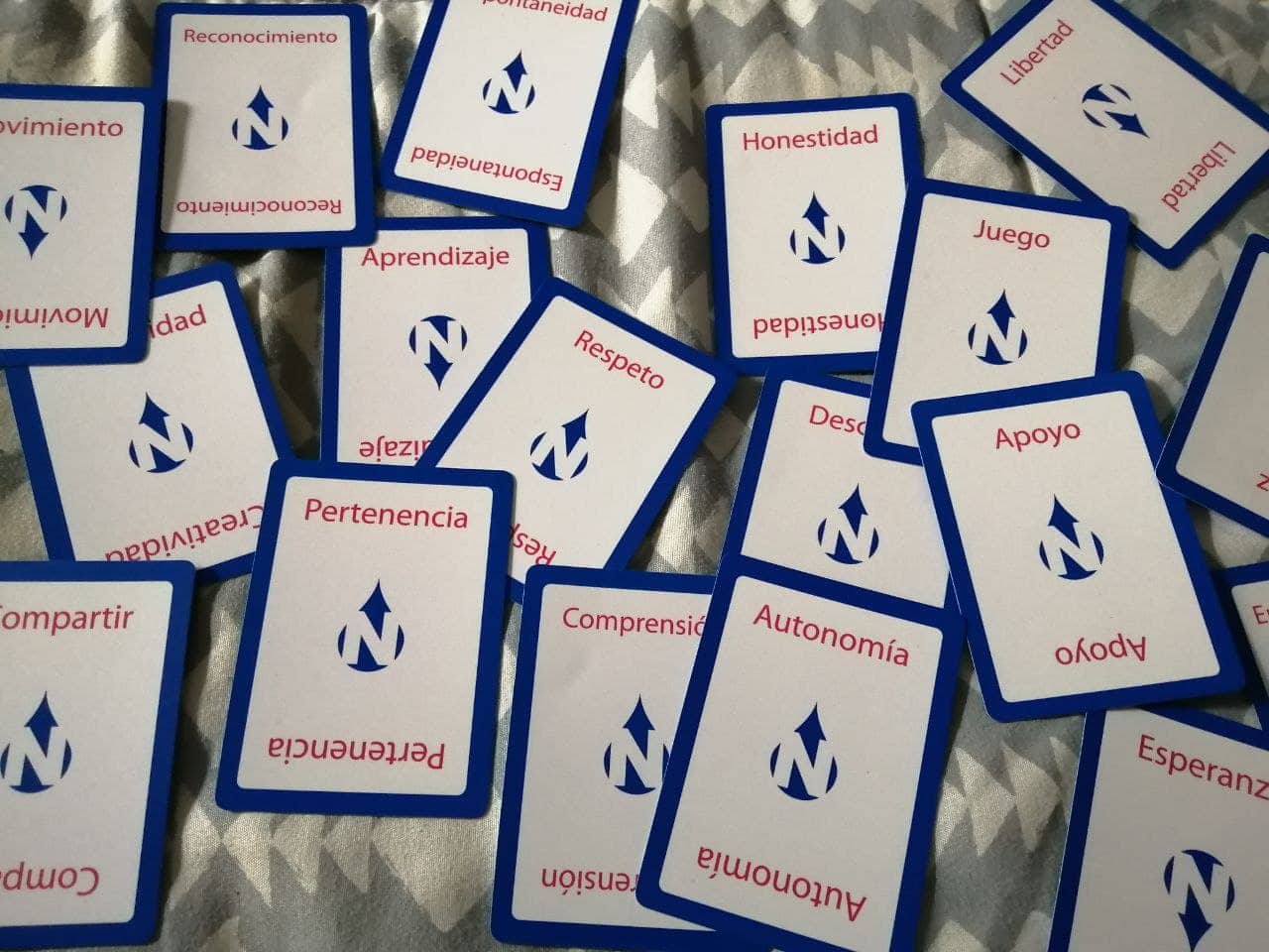 Varias tarjetas con palabras en español como "Reconocimiento", "Honestidad", "Juego" y "Respeto" están esparcidas sobre una superficie estampada.