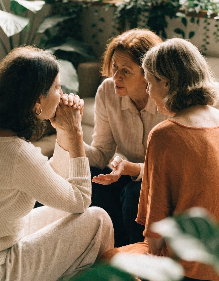 Mujeres mayores conversando y apoyándose en un ambiente cálido y acogedor.