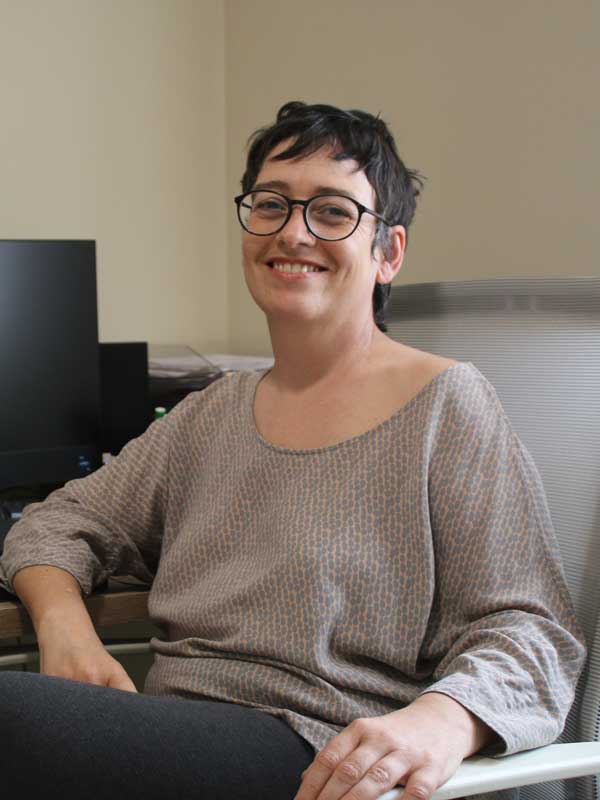 Mujer sonriente con gafas en oficina, imagen profesional y amigable.