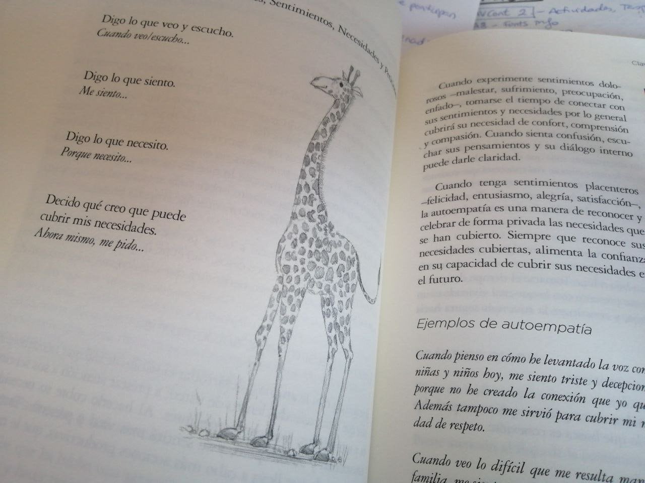Libro abierto en español con un dibujo de una jirafa en la página izquierda y texto impreso en ambas páginas; en el fondo se aprecian parcialmente notas manuscritas.
